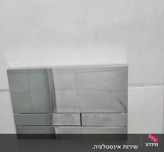 לחצן הדחה כסוף על קיר אריחים לבנים
